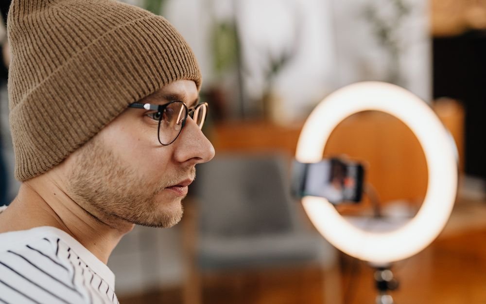 A content creator recording video with a ring light and smartphone